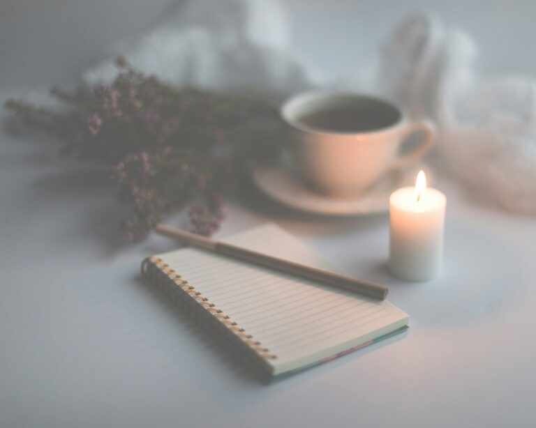 A journal, candle, coffee, and flowers on a desk of a person reflecting on how to set healthy boundaries.