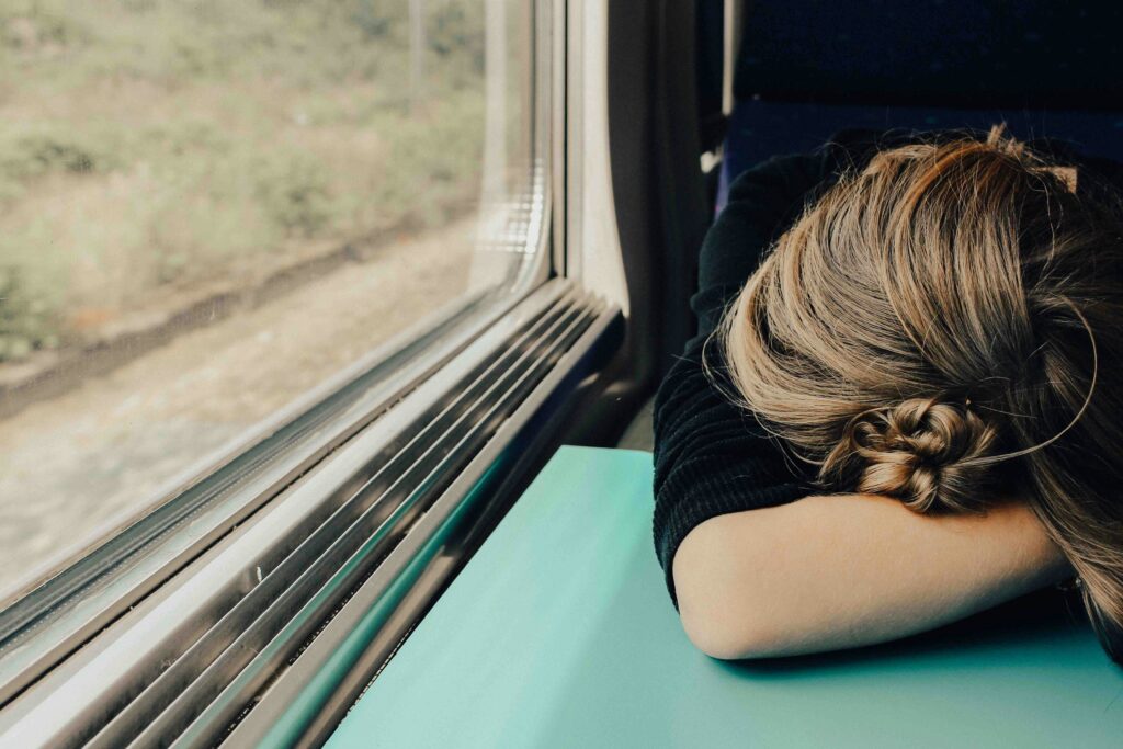 Woman resting their head on a table inside a train after spending all of their mental energy.