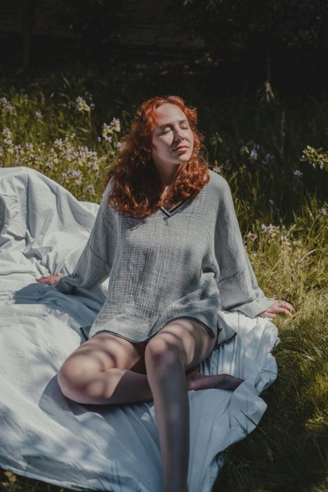 Person resting on a blanket in a field thinking about mindfulness and the benefits of meditation.